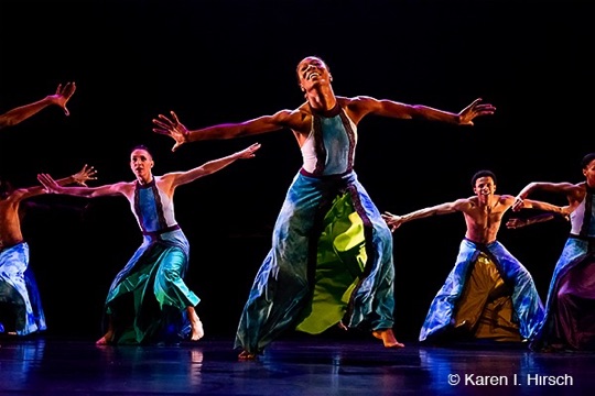 Female African-American dancer with extended arms joyous in a group of dancers